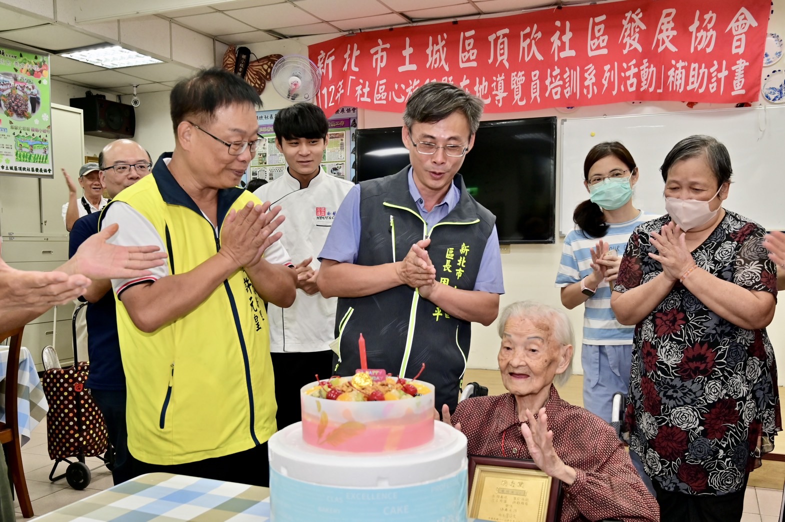 頂新里長許元皇為祝福里內龍桂英阿嬤今年滿百歲，特別在巿民活動中心準備大蛋糕慶賀。